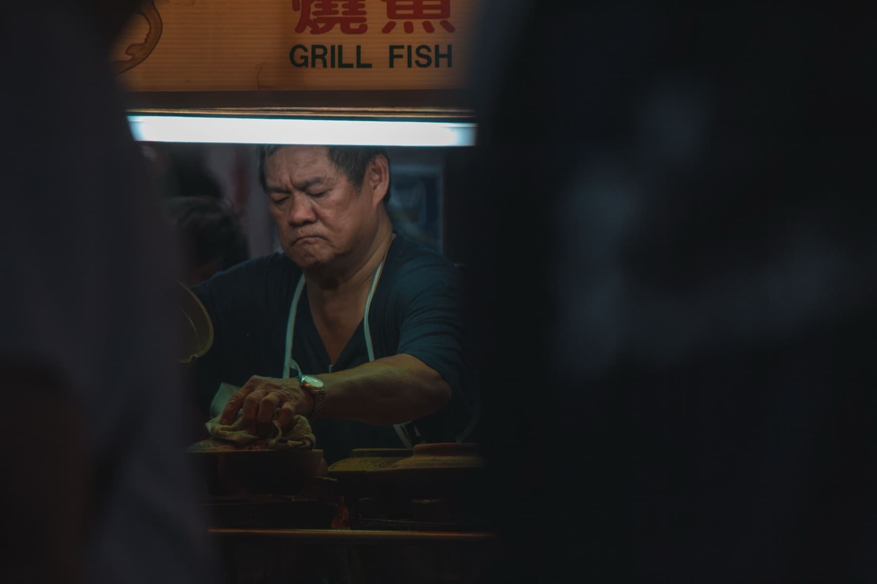 A vendor grilling fish at night